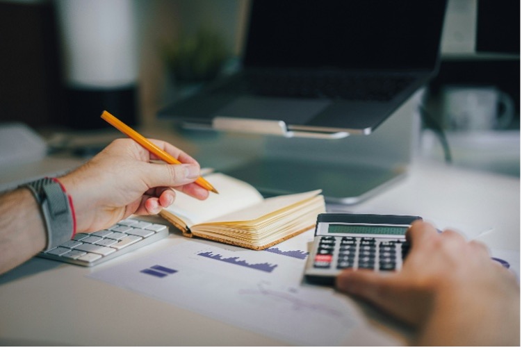 Person writing and using a calculator